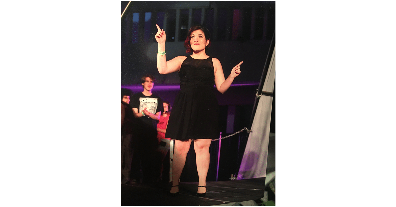 Domi La Russa as a CalArts student on stage wearing a black dress.
